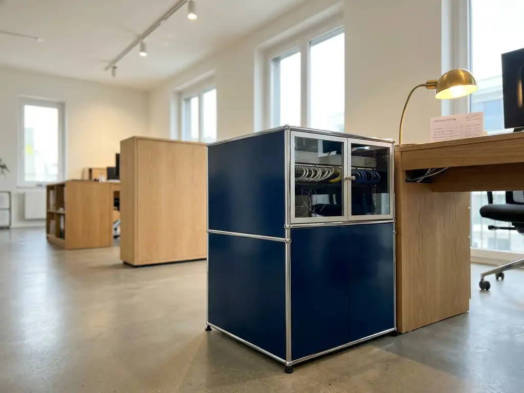 Kompaktes Server-Rack in modernem deutschem Büro mit Kostenschätzung auf dem Schreibtisch, kühle Silber- und Marineblautoene.