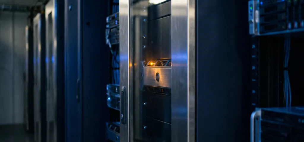 Serverrack in dunklem Rechenzentrum-Gang mit warmem Bernstein-Statuslicht und kühlem Blauambiente auf Metalloberflächen.