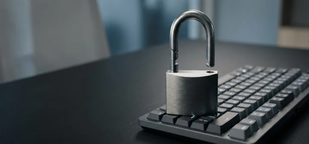 Leicht geöffnetes Vorhängeschloss auf dunkler Laptop-Tastatur, symbolisiert Cybersicherheitslücke.